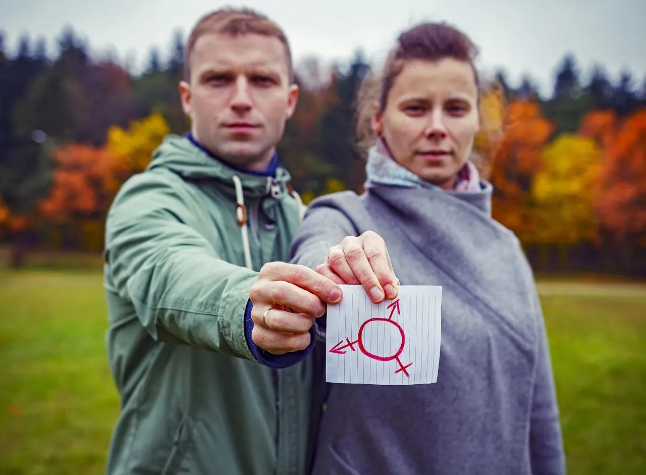 Male and female together holding piece paper with drawing transgender symbol. Human sex rights. Gender symbol in hands of man and woman